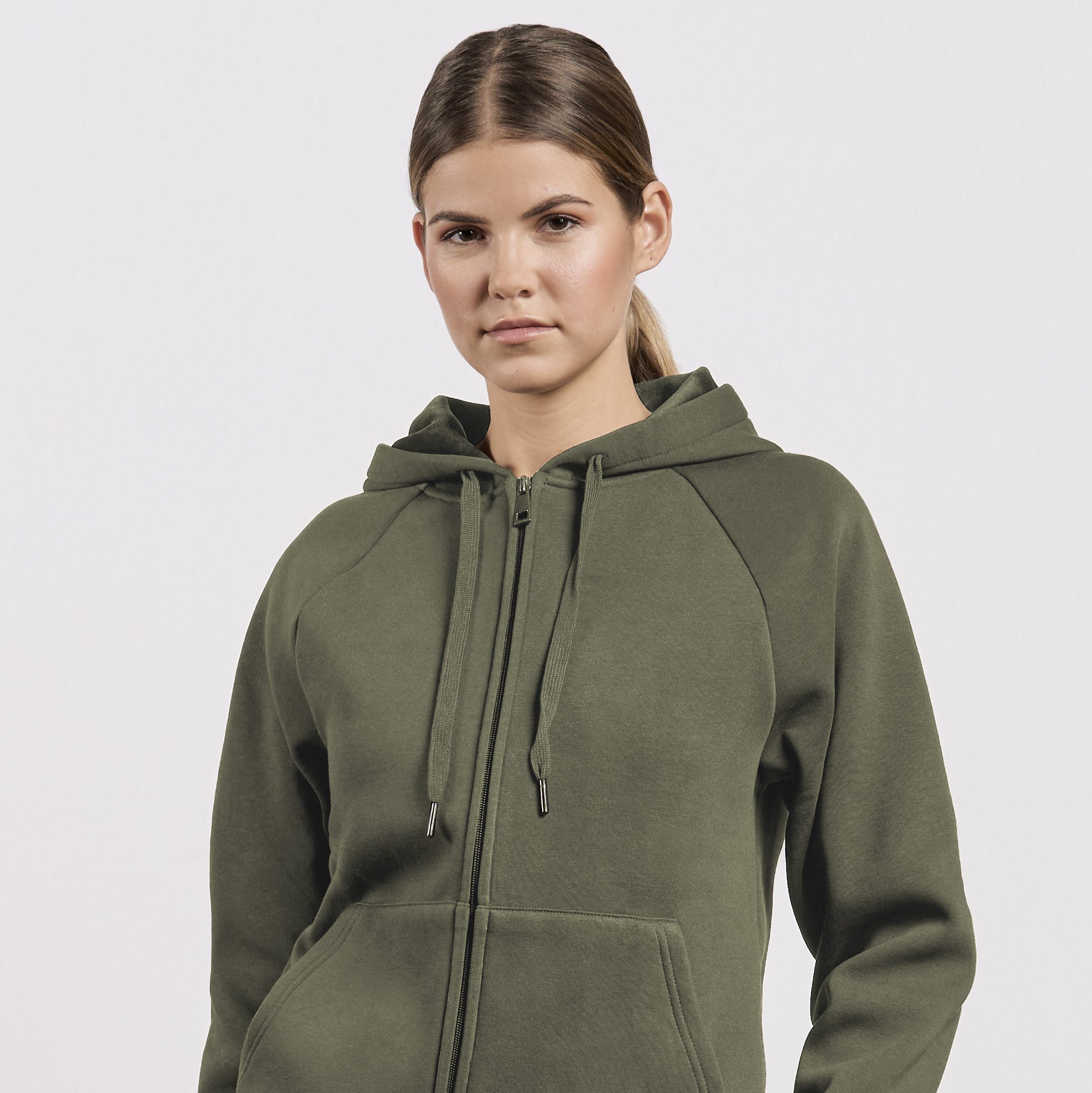 Frau trägt eine schlichte, khakifarbene Hoodie-Jacke mit Reißverschluss. Ein funktionales Basic für kühlere Tage im minimalistischen Stil.